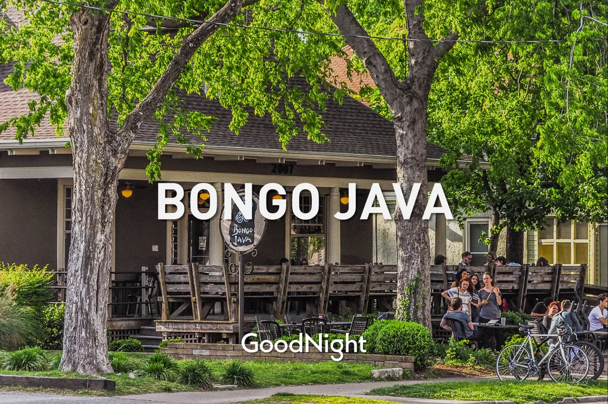 A welcoming exterior of a local café with a Bongo Java sign, wooden seating under leafy trees, and bicycles parked nearby. The setting encourages outdoor relaxation and socializing in a pet-friendly, community-oriented spot.