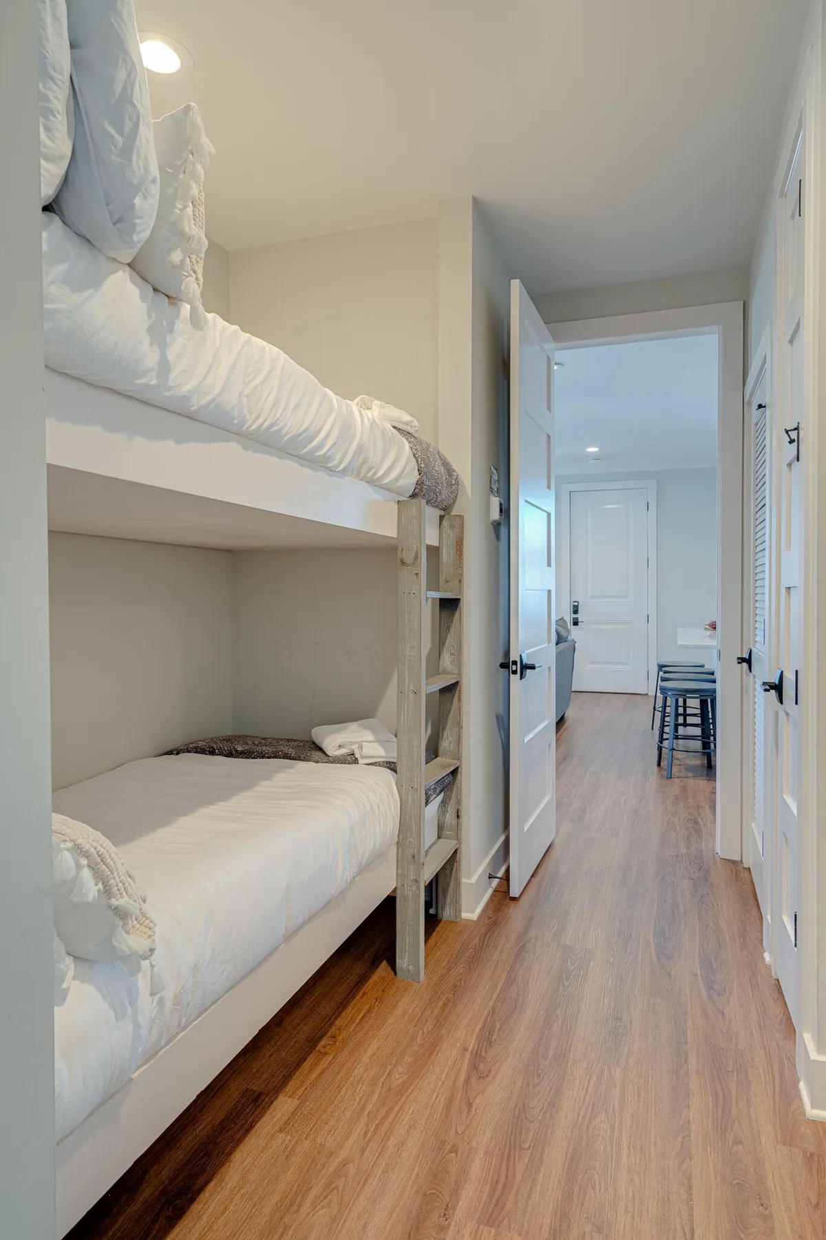 A playful, comfortable nook with built-in twin bunk beds topped with textured blankets, accessed by a sturdy wooden ladder. The space is designed for fun and connection, ideal for kids or adventurous guests, and radiates a cozy, inviting mood.